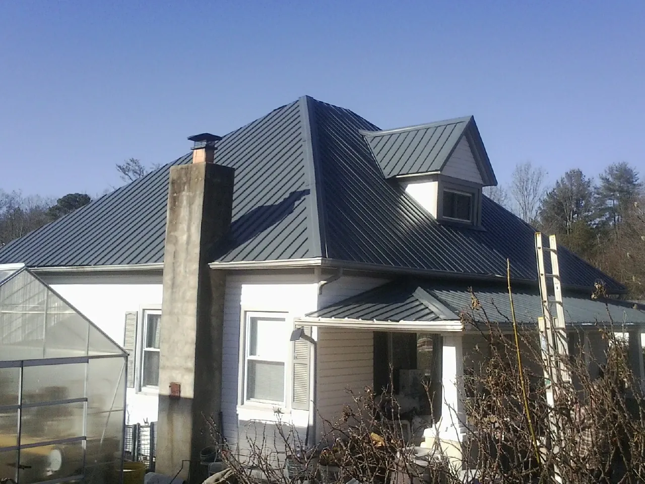 Dark blue standing seam metal roof on a white farmhouse with dormer — Slate & Tile Roof Repair by Roofing Brothers in Chimacum