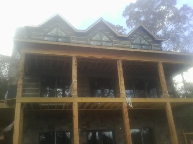 Dormers and porch framing on a large log home under construction — Roof Coating work by our crew in Chimacum