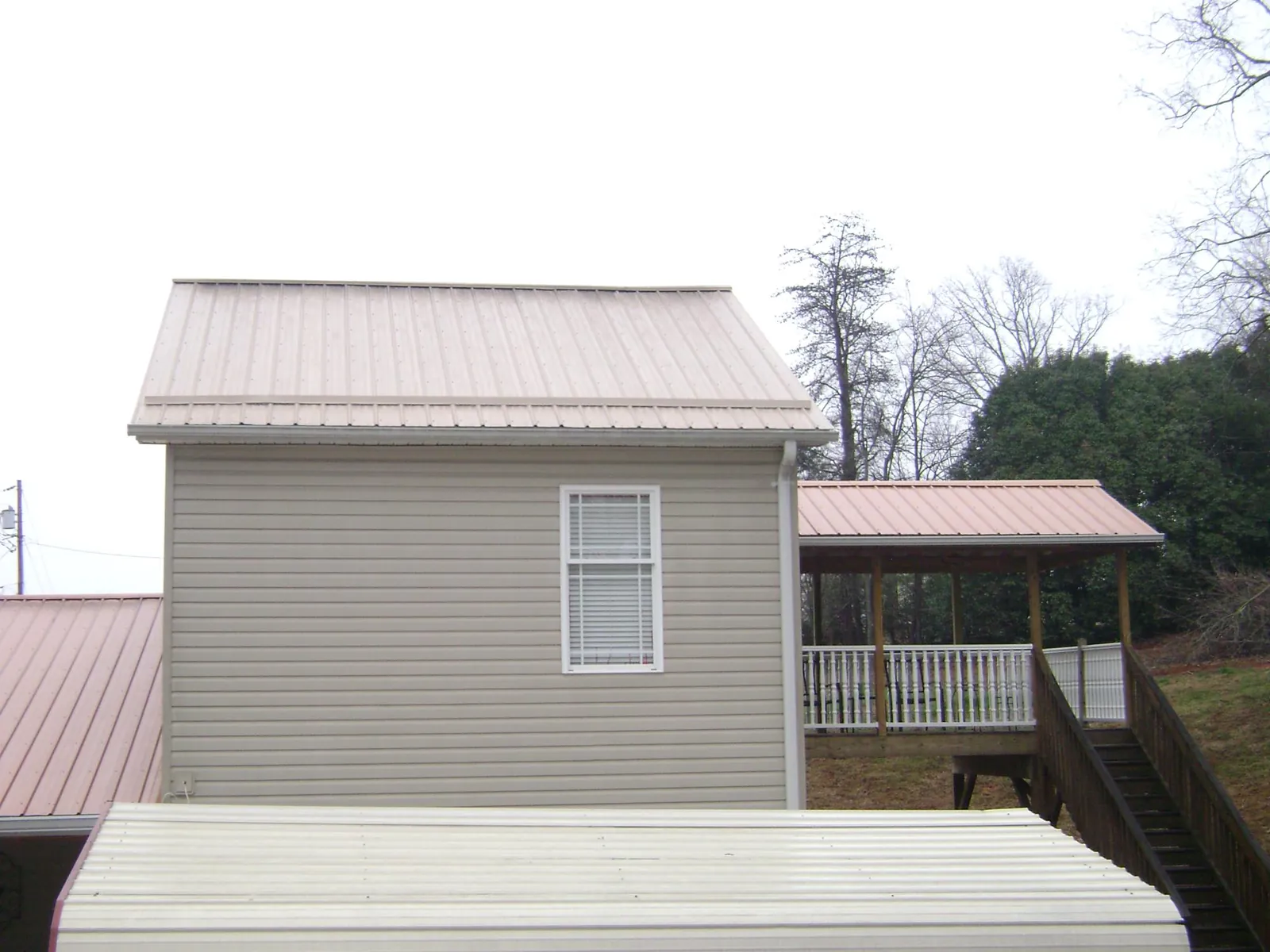 Tan metal roofs on a two story addition and attached porch, from a Roof Replacement job in Chimacum
