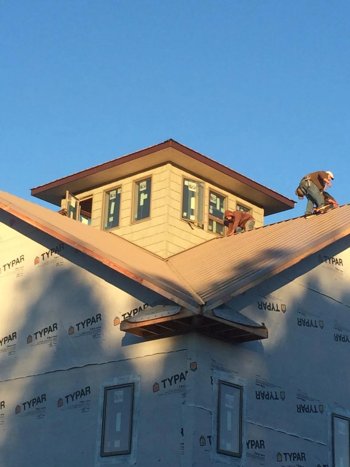 Roofers working around a rooftop cupola on a new metal roof at sunset — Roof Waterproofing in Chimacum by Roofing Brothers